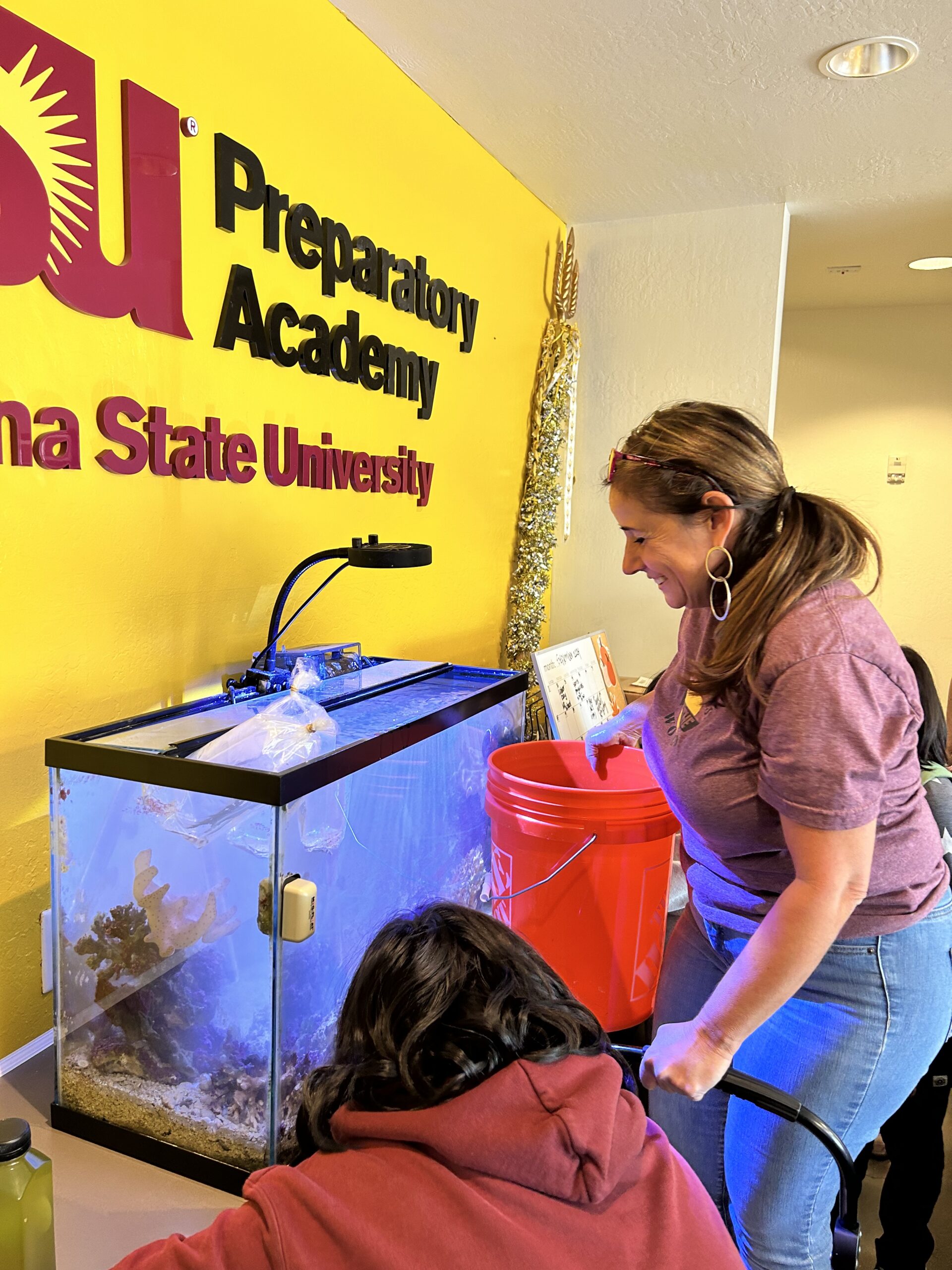 A student and teacher look into a fish tank