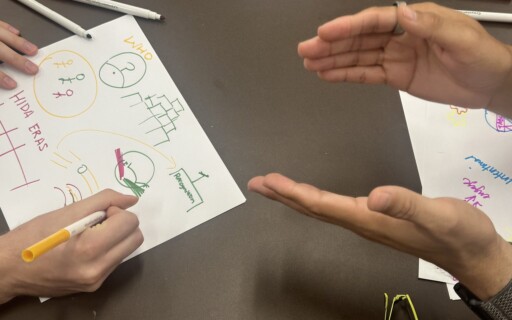 A close-up of people's hands drawing at a workshop.