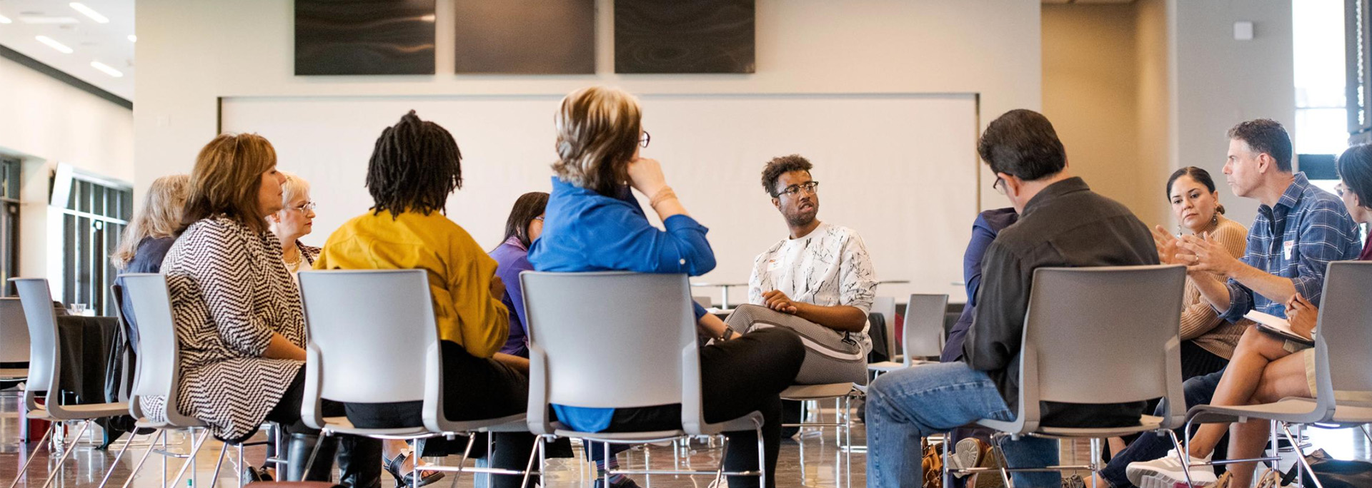ASU students, faculty and staff sit in chairs in a circle, engaged in dialogue