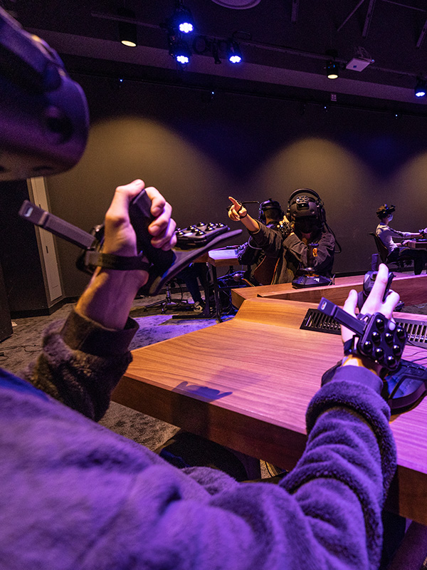 Four students wearing VR headgear and using hand controls