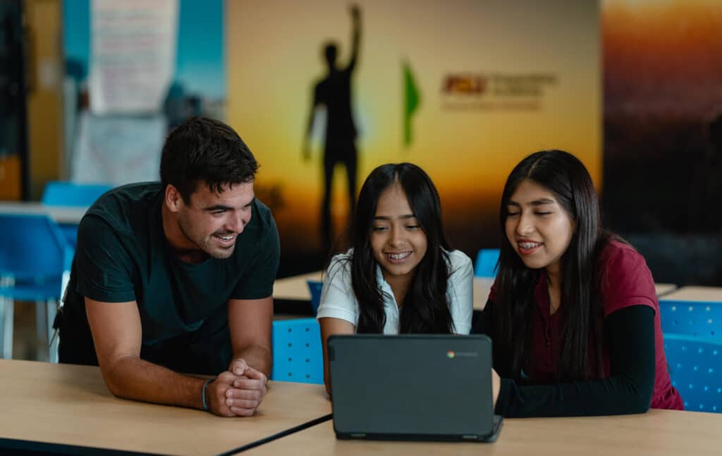 A teacher looking at a laptop with a student