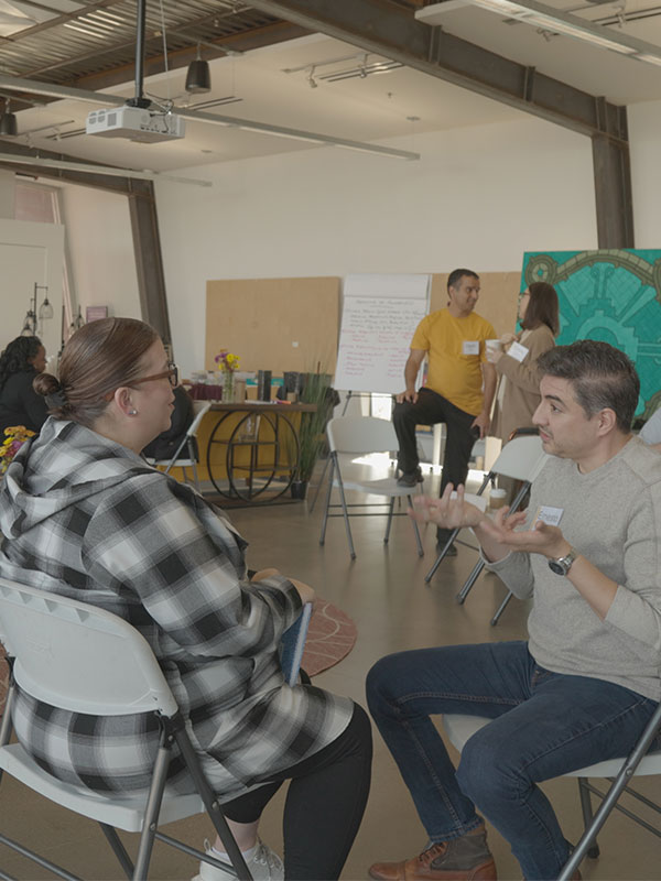 Two people seated in folding chairs engaged in animated conversation